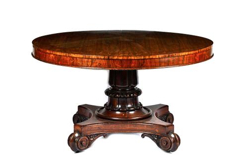 A William IV rosewood breakfast table, the circular snap top on a substantial lappet carved column, with quatrefoil platform and scroll feet, 133cm wi