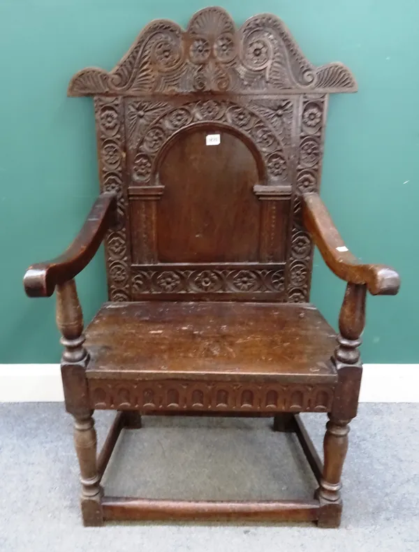 A late 17th century and later carved oak high back armchair in the Yorkshire style, floral lunette and scroll carved with serpentine top rail, arched