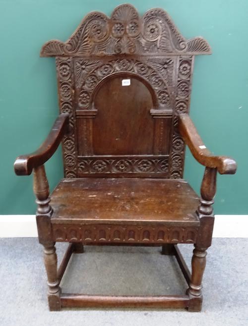 A late 17th century and later carved oak high back armchair in the Yorkshire style, floral lunette and scroll carved with serpentine top rail, arched