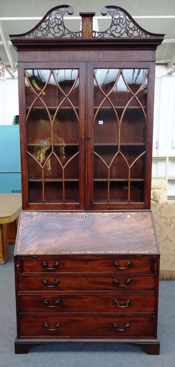 A George III mahogany bureau bookcase, the pierced scrolling swan neck pediment above a pair of astragal glazed doors, with fitted interior above four