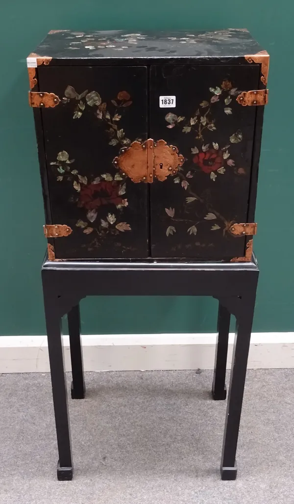 A 19th century Chinese ebonised and mother-of-pearl inlaid small cabinet on stand, the twin door cabinet with floral decoration and multi-drawer inter