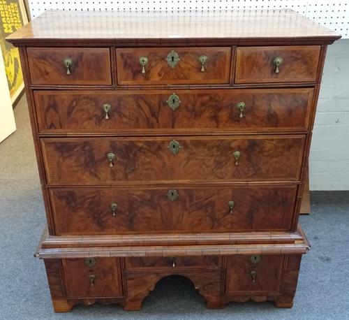 An early 17th century walnut chest on stand, the chest with three short and three long graduated drawers, the base with three drawers about the arched