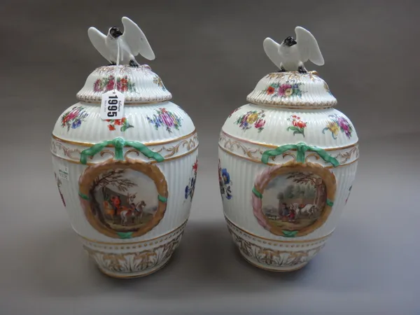 A pair of Berlin porcelain ovoid fluted vases and covers, late 19th/early 20th century, each painted with panels of figures and horses within moulded