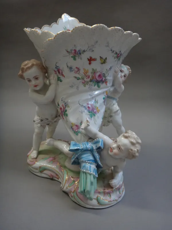 A Paris porcelain centrepiece, late 19th century, modelled as three putti holding a floral painted cornucopia vase, on a scroll moulded base, green an