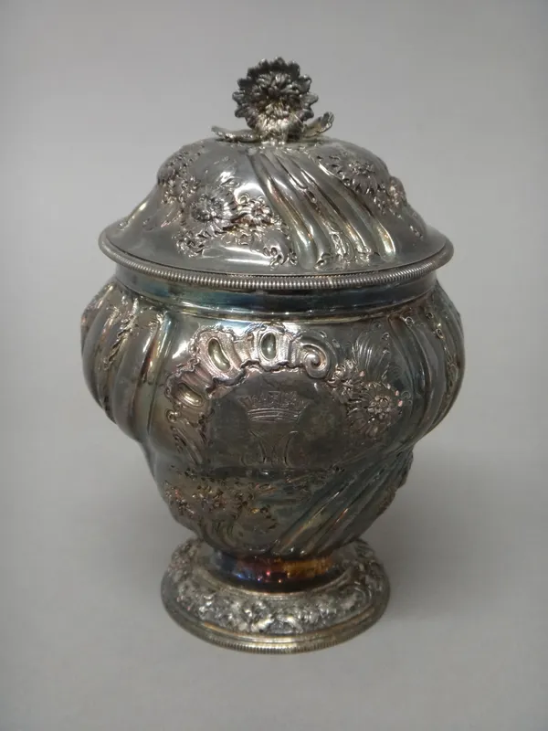 A George II silver sugar vase and cover, gilt within, the body embossed with floral sprays between spiral fluted bands and raised on a circular foot,