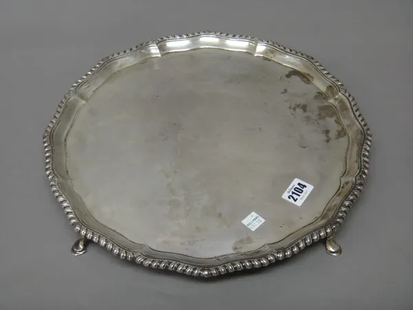 A silver salver, of shaped circular form, decorated with a gadrooned rim and raised on four pad feet, London 1948, diameter 36cm, weight 1400 gms.