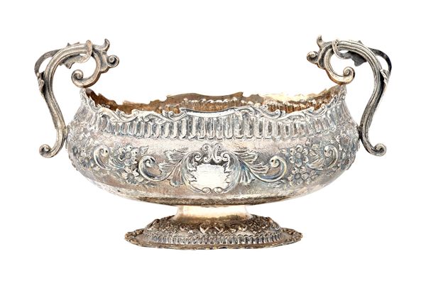 A silver twin handled large bowl, of shaped oval form, with floral, foliate and scroll embossed decoration, raised on a shaped oval foot and having ca