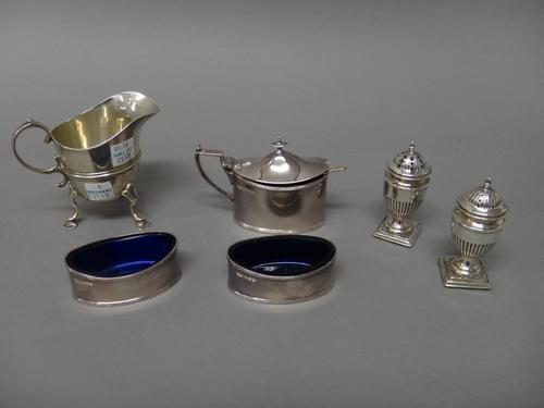 Silver, comprising; a helmet shaped milk jug, raised on three feet, London 1901, an oval mustard pot, Sheffield 1916, with a blue glass liner, a later