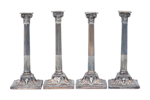 A set of four George III silver table candlesticks, each formed as a Corinthian column with ram's head masks to the corners of the capital, raised on