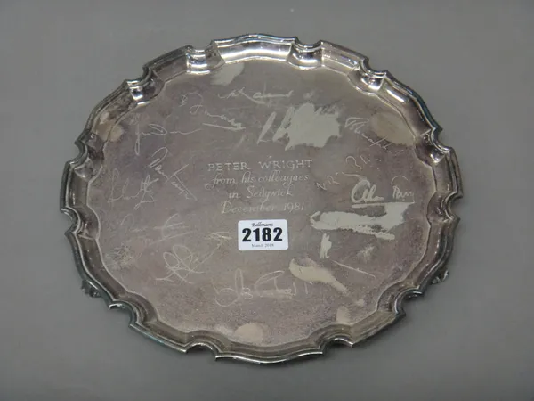 A silver salver of shaped circuclar form, having a piecrust rim, raised on three scrolling feet, presentation inscribed, diameter 25.5 cm, Sheffield 1