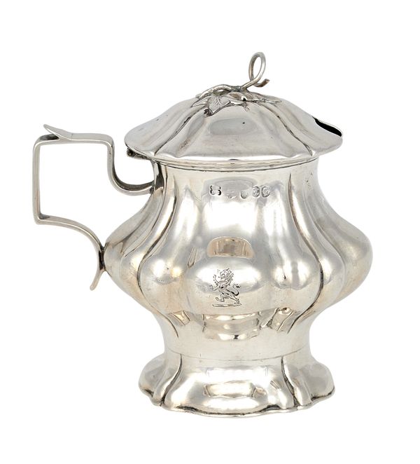 A Victorian silver hinge lidded mustard pot, of squat bulbous form with partly fluted decoration, crest engraved, raised on a shaped circular foot, he