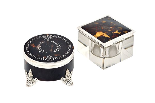 A silver and tortoiseshell circular hinge lidded trinket box, the cover inlaid with floral sprays within a pierced scrolling border and raised on four