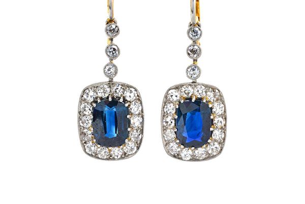 A pair of sapphire and diamond pendant cluster earrings, each with three articulating collet set diamonds above an oval mixed cut sapphire, claw set w