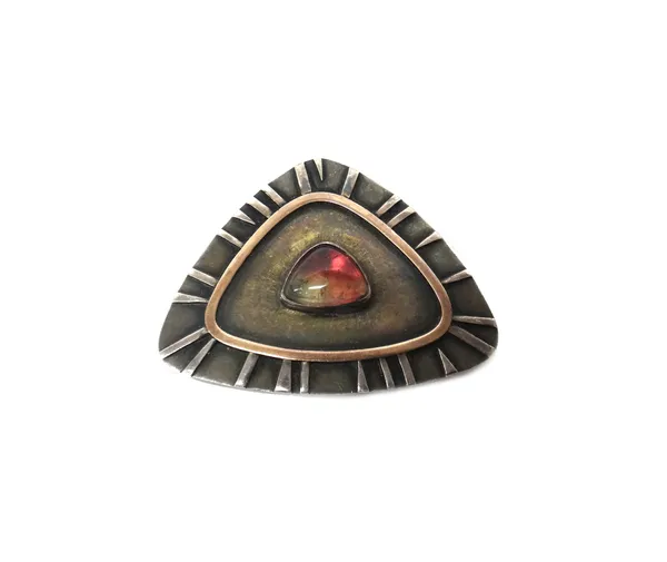 A silver mounted cabochon vary coloured tourmaline shaped triangular brooch, having a decorated border outside a gilt rim, length 5cm.