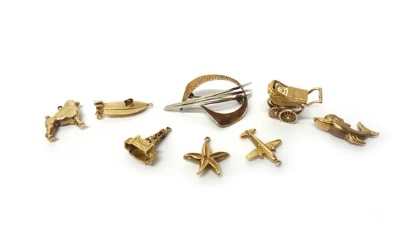 Seven 9ct gold charms, including; a pram, an aeroplane, a starfish, a poodle and a dolphin and a 9ct gold brooch in an abstract design, combined weigh