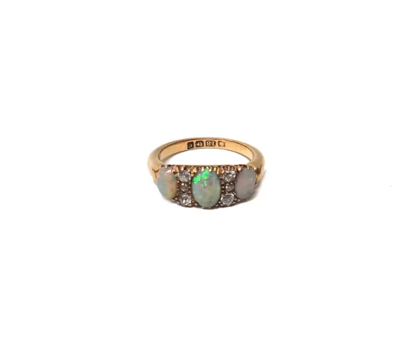 An 18ct gold, opal and diamond set ring, mounted with three oval opals and with two rows of cushion shaped diamonds mounted at intervals, Birmingham 1