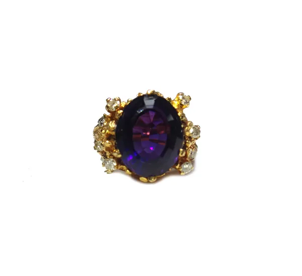 A gold, amethyst and diamond set ring, in an abstract design, claw set with the oval cut amethyst at the centre, between diamond set four stone sides,