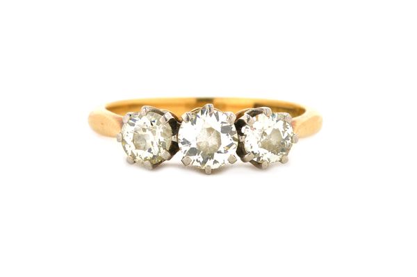 A gold and platinum, diamond set three stone ring, claw set with a row of cushion shaped diamonds, detailed 18 C & PLAT, ring size M.  Illustrated