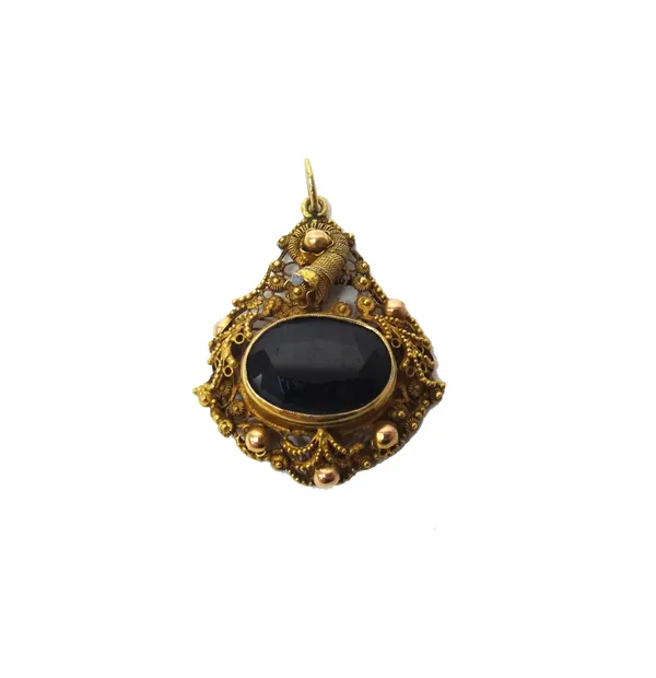 A gold filigree and garnet set single stone pendant, collet set with an oval cut garnet, within a beaded surround.