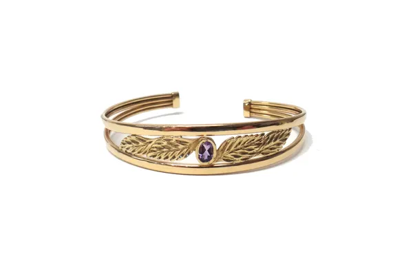 A 9ct gold and amethyst set bangle, collet set with an oval cut amethyst between foliate pierced sides, gross weight 7 gms.