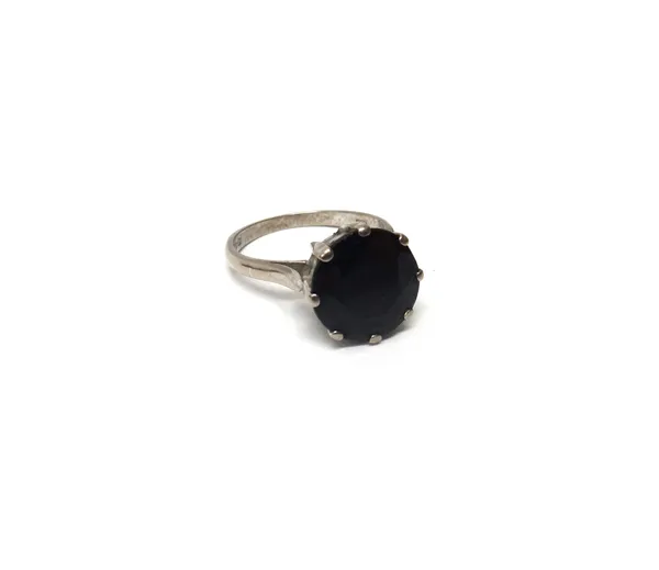 An 18ct white gold ring, claw set with a circular cut dark sapphire, London 1981, ring size N and a half, with a case.