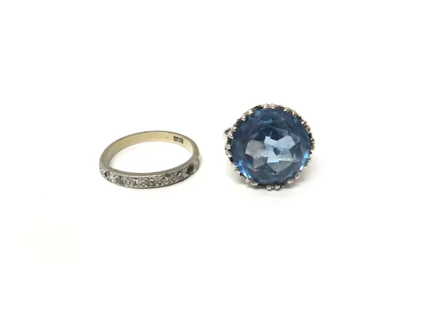 A white gold ring, claw set with a circular cut synthetic blue spinel, ring size L and a half and a white gold and diamond set half hoop eternity ring