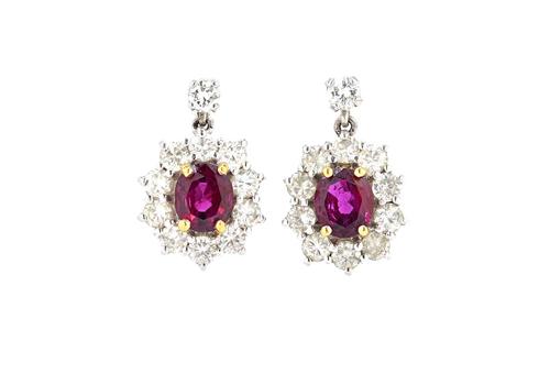 A pair of 18ct white gold, ruby and diamond set oval cluster earrings, each claw set with an oval cut ruby at the centre, in a surround of circular cu