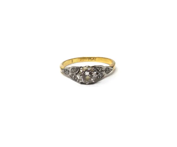 A gold and platinum, diamond set ring, claw set with the principal circular cut diamond at the centre, between diamond set three stone foliate shoulde