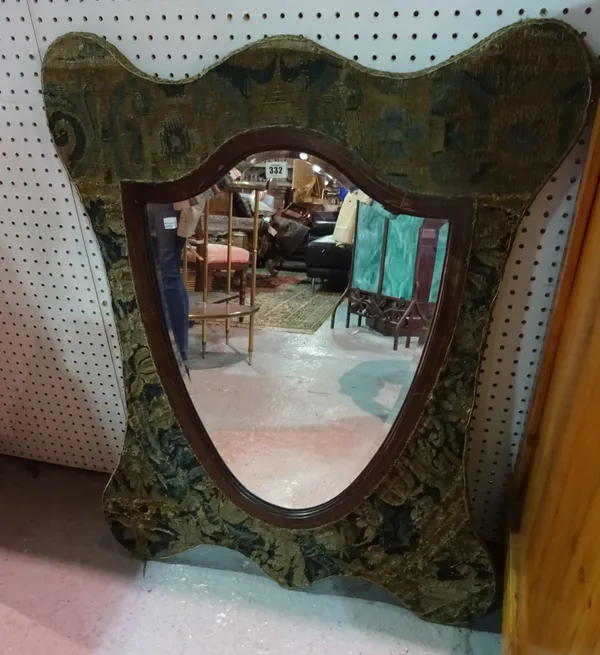 A mahogany framed shield shaped mirror, within a serpentine upholstered frame, 77cm wide x 97cm high.  A4