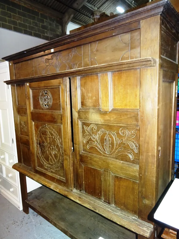 An early 20th century Breton cupboard, with sliding panel door decorated with flags and anchors, 185cm wide x 200cm high.  M7