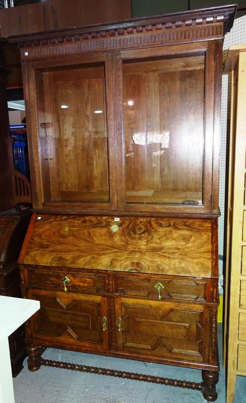An Edwardian oak and walnut bureau bookcase, with geometric panelling, on bun feet united by a bobbin turned stretcher, 135cm wide x 215cm high.  M6