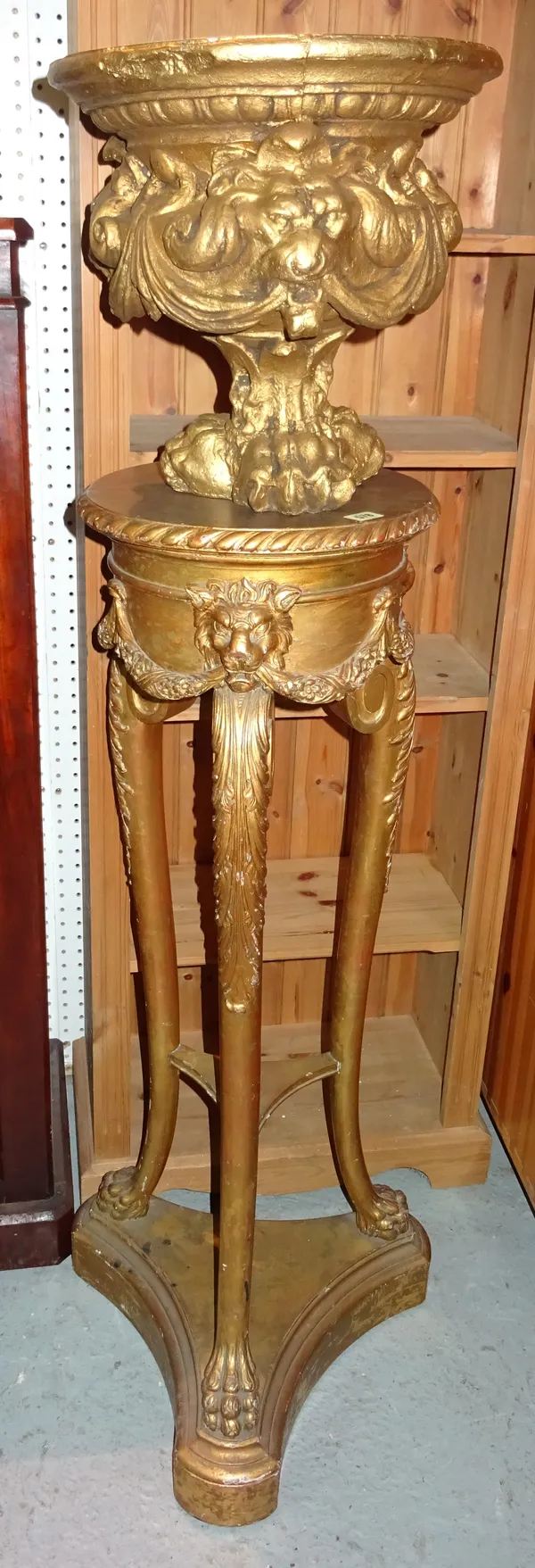 A George III style giltwood jardiniere stand on three scroll supports with lion mask and floral swag decoration on claw feet, 34cm wide x 114cm high a