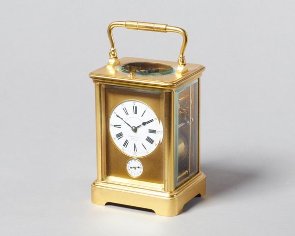 A French gilt brass carriage clockCirca 1910In a corniche case with push/repeat, with bevelled glass panels, the circular white enamel dial inscribed