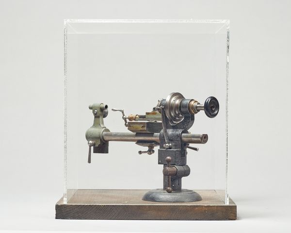 A perspex cased watchmaker's lathe27cm. square.  Illustrated