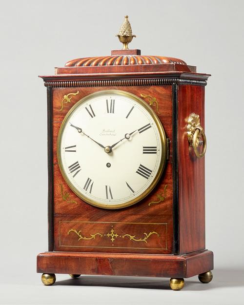 A late Regency mahogany and cut-brass inlaid bracket timepieceThe case with a gadrooned pediment, surmounted by a pineapple finial, with a pair of rin