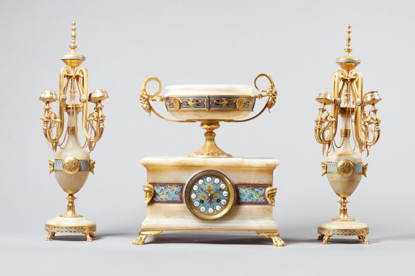 A French ormolu, champleve enamel and onyx clock garnitureIn the Grecian style, circa 1890The clock surmounted by an urn with scrolled handles, the