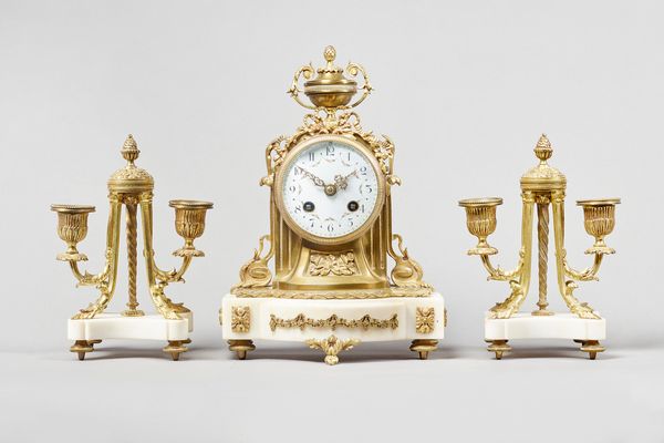 A French giltmetal and marble garnitureIn the Louis XVI style, circa 1900Surmounted by an urn with ribbon tied foliage above the white enamel dial wit