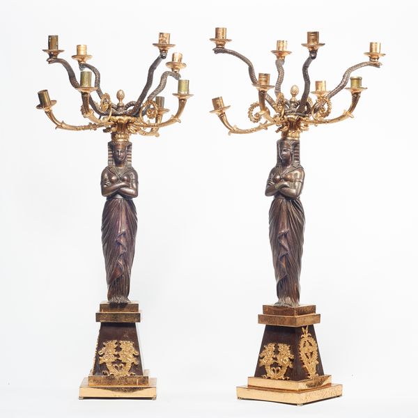 A pair of Empire style gilt and patinated bronze eight branch figural candelabra, 20th century, each Egyptian female figure supporting serpent cast br