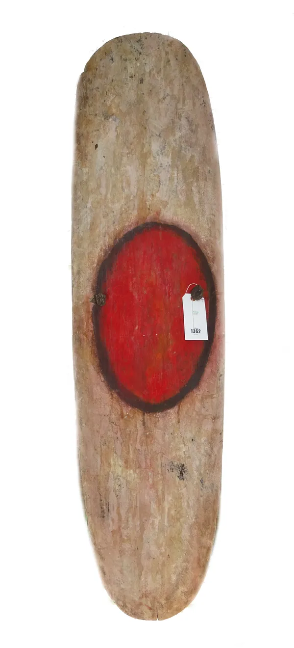 A shaped wooden war shield, Papua New Guinea, 20th century, with central painted red circle and rope handle, 146cm high x 42cm wide.