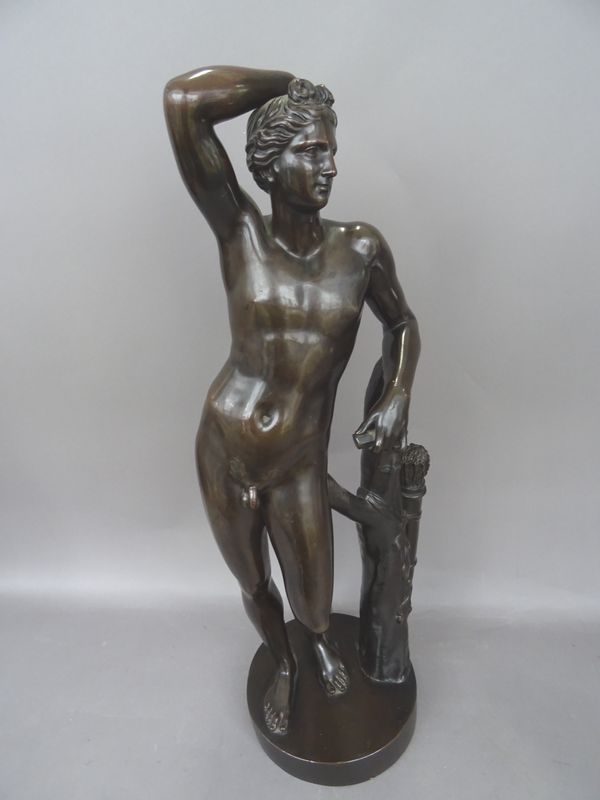 A Victorian style patinated bronze of a male nude, early 20th century, modelled leaning against a tree trunk, with quiver of arrows on a circular base