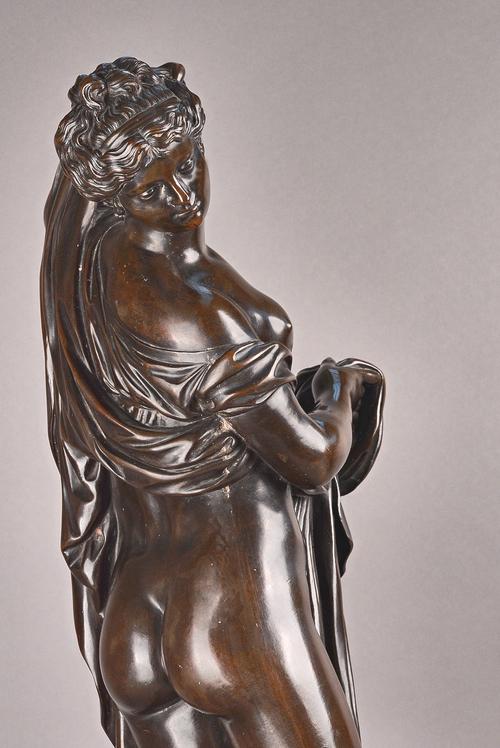 A Victorian style patinated bronze, cast as a semi-nude classical female figure, early 20th century, in a long flowing robe, on a circular base, unsig