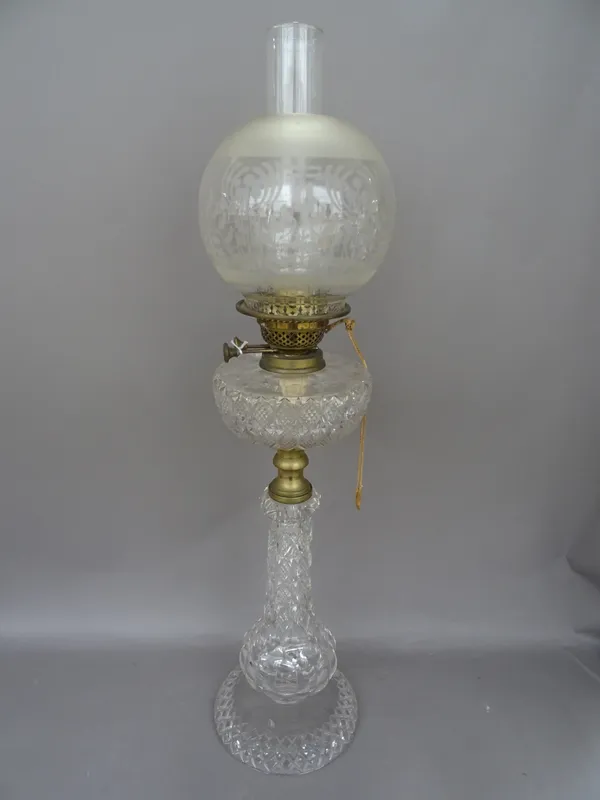 An Edwardian cut glass oil lamp, with matching reservoir, gilt metal burner and a later clear glass shade of globular form, 77cm high overall.