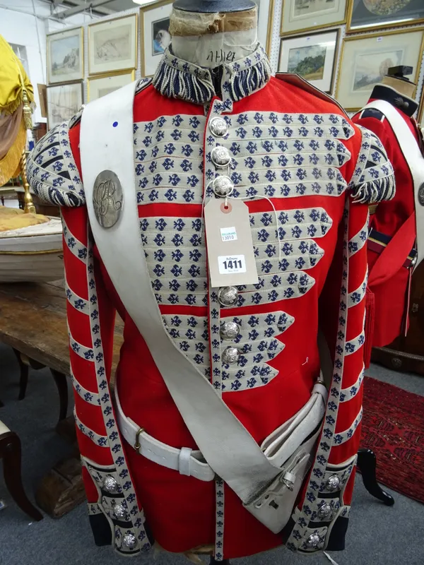 A Scottish military officer's red tunic, sash and belt, displayed on an ebonised wood and shaped tailor's dummy, 160cm.