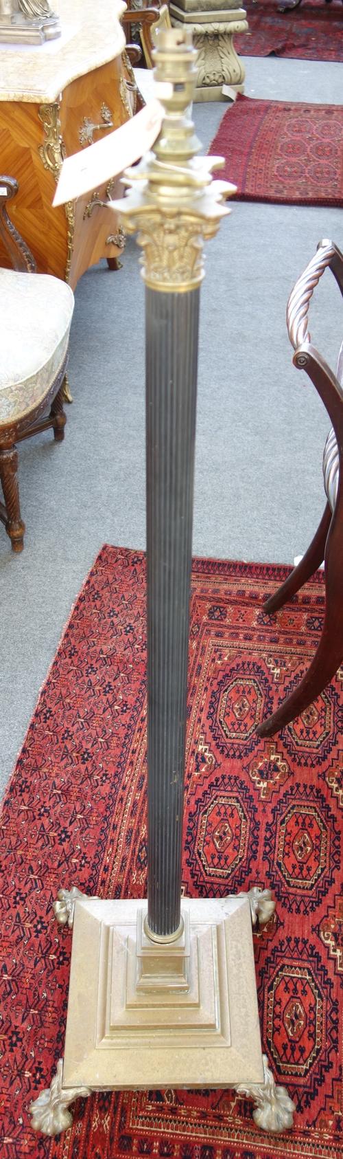 A Victorian brass adjustable standard lamp, of Corinthian column form, on a stepped square base and four lion paw feet, together with another similar