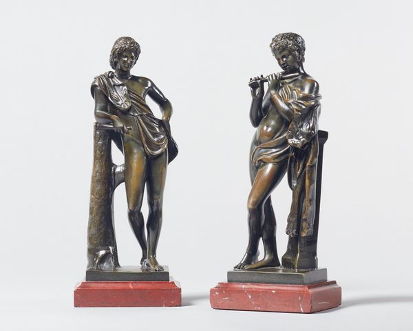 A pair of patinated bronze semi-nude male figures, late 19th century, each of classical form playing a flute on a rouge marble rectangular plinth, ind
