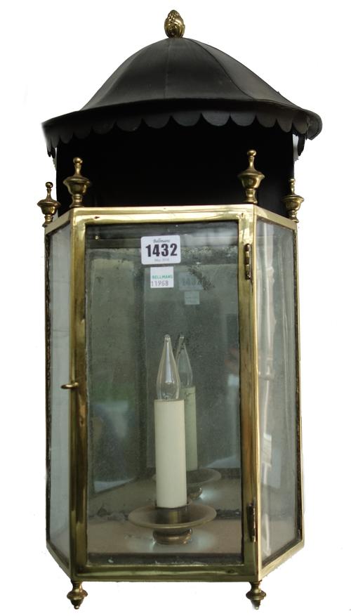 A George III brass wall lantern of canted rectangular form with turned finials, a mirrored back plate and a later pagoda top, 54cm high.