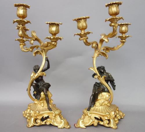 A pair of French ormolu three branch figural candelabra, 19th century, the foliate branches supported by partially clothed classical figures on a pier