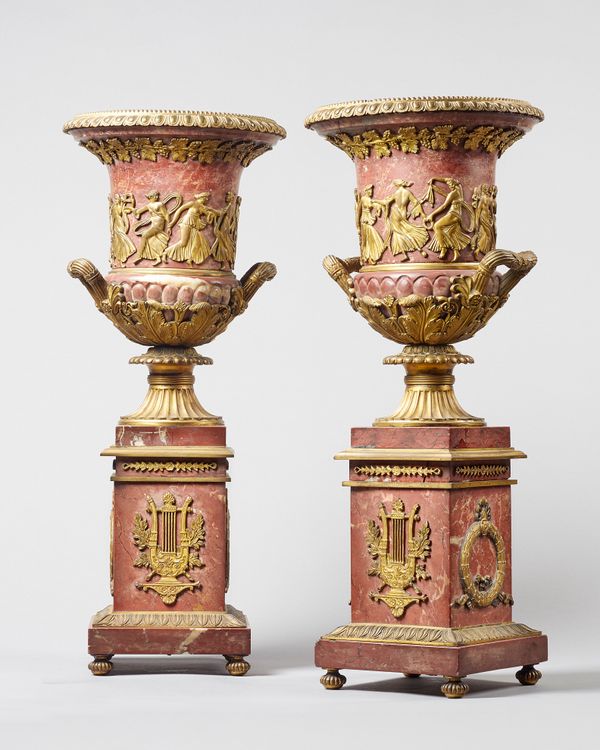 A pair of French ormolu mounted rouge marble campana urns, 19th century, each raised on a stepped square plinth, 54cm high, (2).  Illustrated