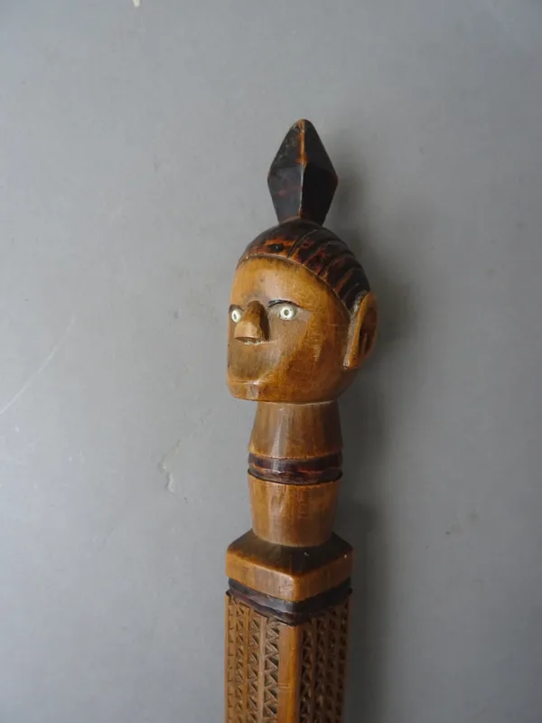 Tribal interest; a hardwood ceremonial walking stick, early 20th century, with carved figure head pommel and square carved grip over a tapering natura