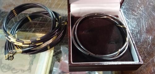 Two gold mounted oxidized metal oval hinged bangles, also a gilt metal mounted five row rubber collar necklace, having a hook shaped clasp, detailed F